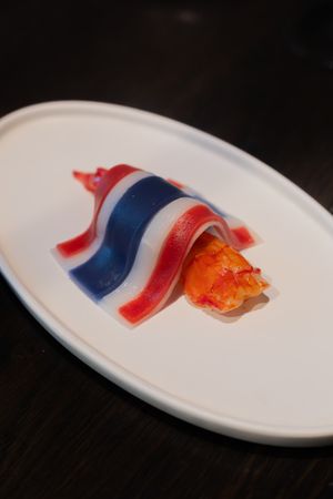 Red, white and blue garnish with orange caviar served on a white curved plate.