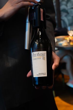 Wine bottles with white labels being displayed in dim lighting.