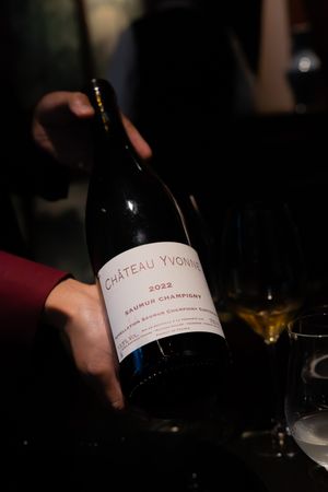 Wine bottle labeled Chateau Yvonne being presented in a dimly lit setting.