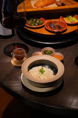 Bowl of white rice served in elegant plating alongside other dishes on a dark wooden table.