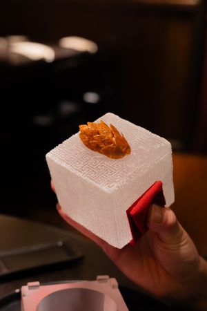 Orange garnish served atop a textured white block in a modern presentation style.