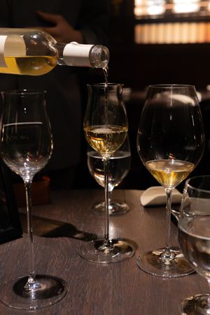 Multiple empty wine glasses arranged on a dark wooden table in a dimly lit restaurant setting.