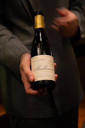 Wine bottles being held and displayed in a dimly lit setting showing elegant labels and packaging.