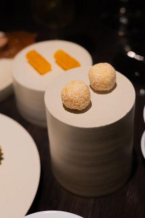 Close-up view of small round truffles or dessert bites served in white ceramic bowls on a dark surface.