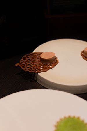 White plates with decorative brown lace-like garnishes arranged on a table.