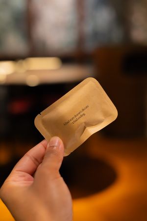 Hand holding a golden-colored packet or envelope in warm lighting.