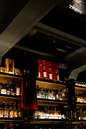 Illuminated bar shelves display bottles of liquor with warm lighting against a dark background in an upscale establishment.