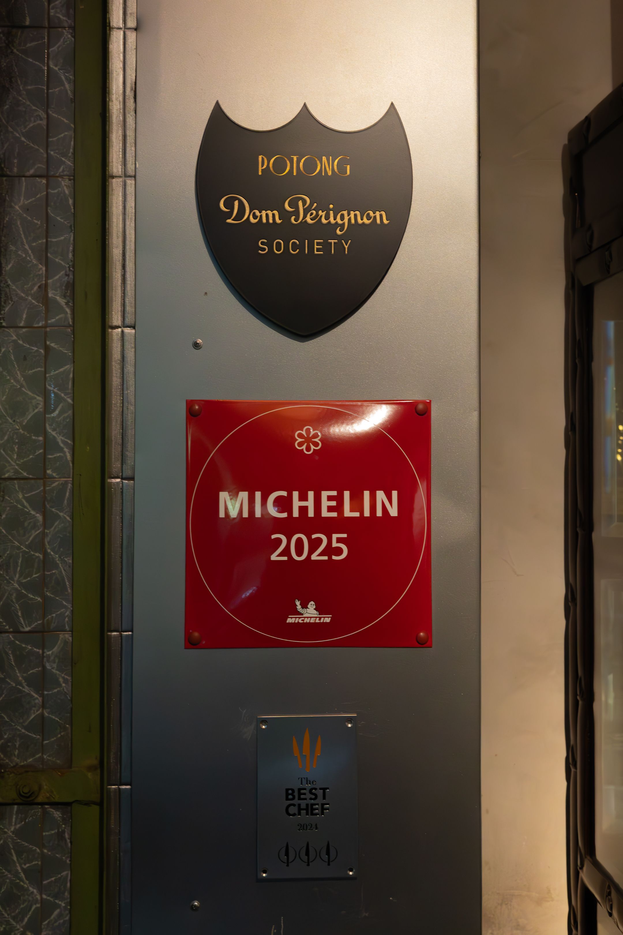 Upscale restaurant wall displaying prestigious Michelin, Dom Perignon, and other luxury hospitality brand plaques.