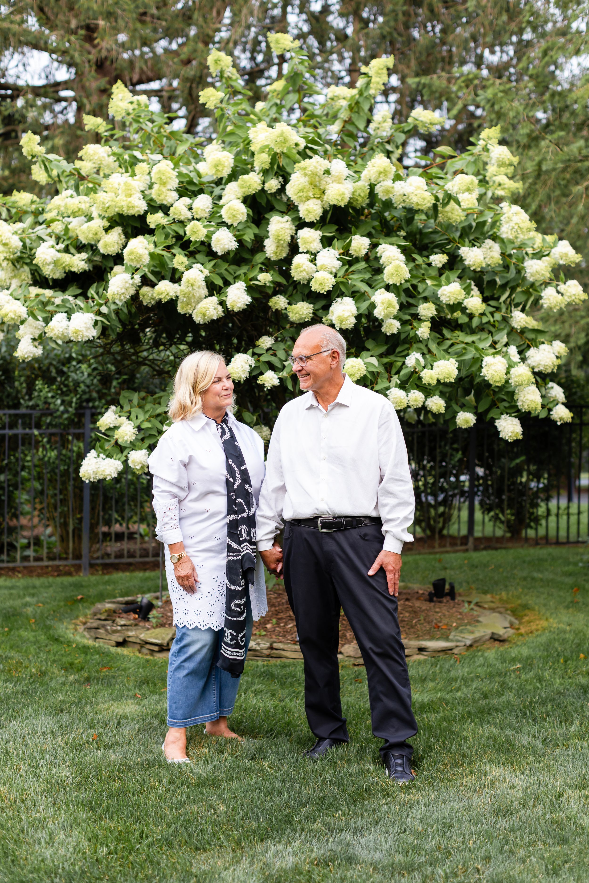 Candid moments captured on a lawn with flowering hydrangea bushes creating a natural backdrop.