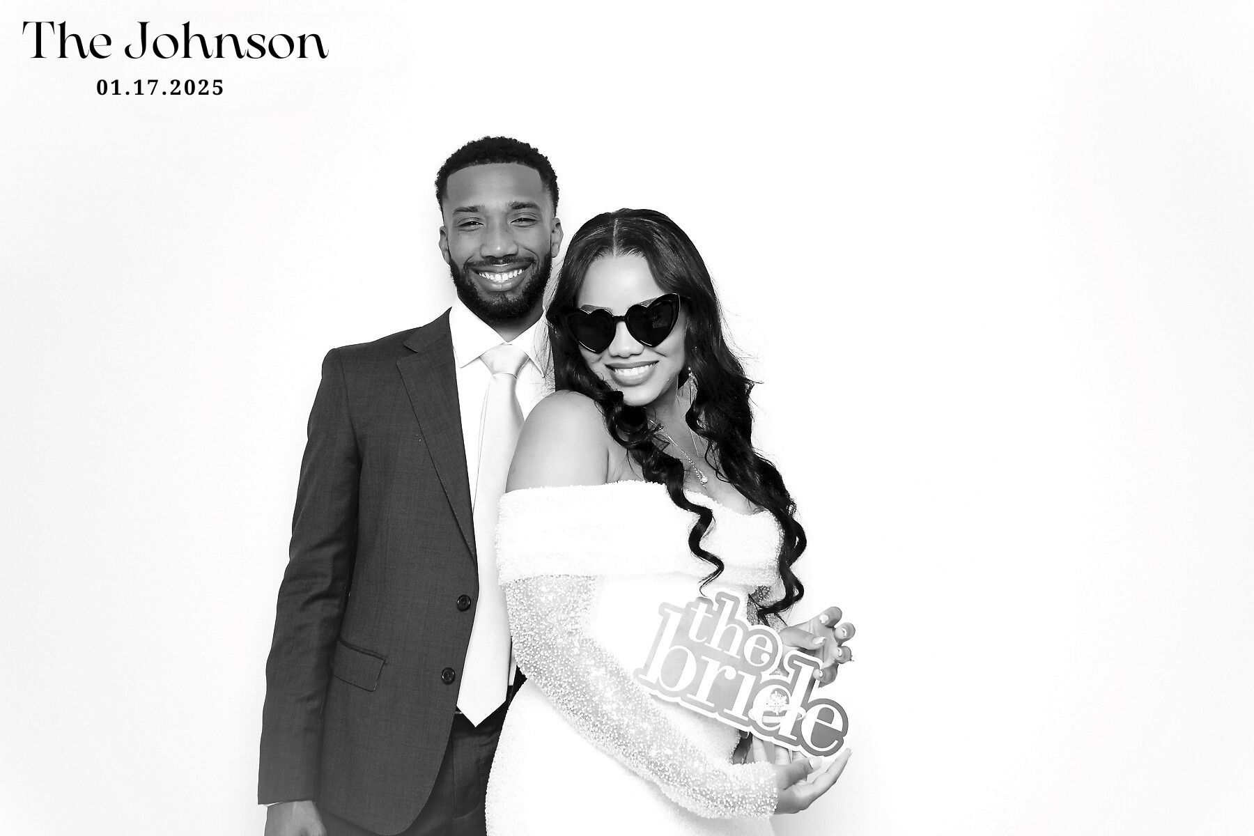 A black and white wedding photo showing a couple in formal attire with the bride in white and groom in dark suit.