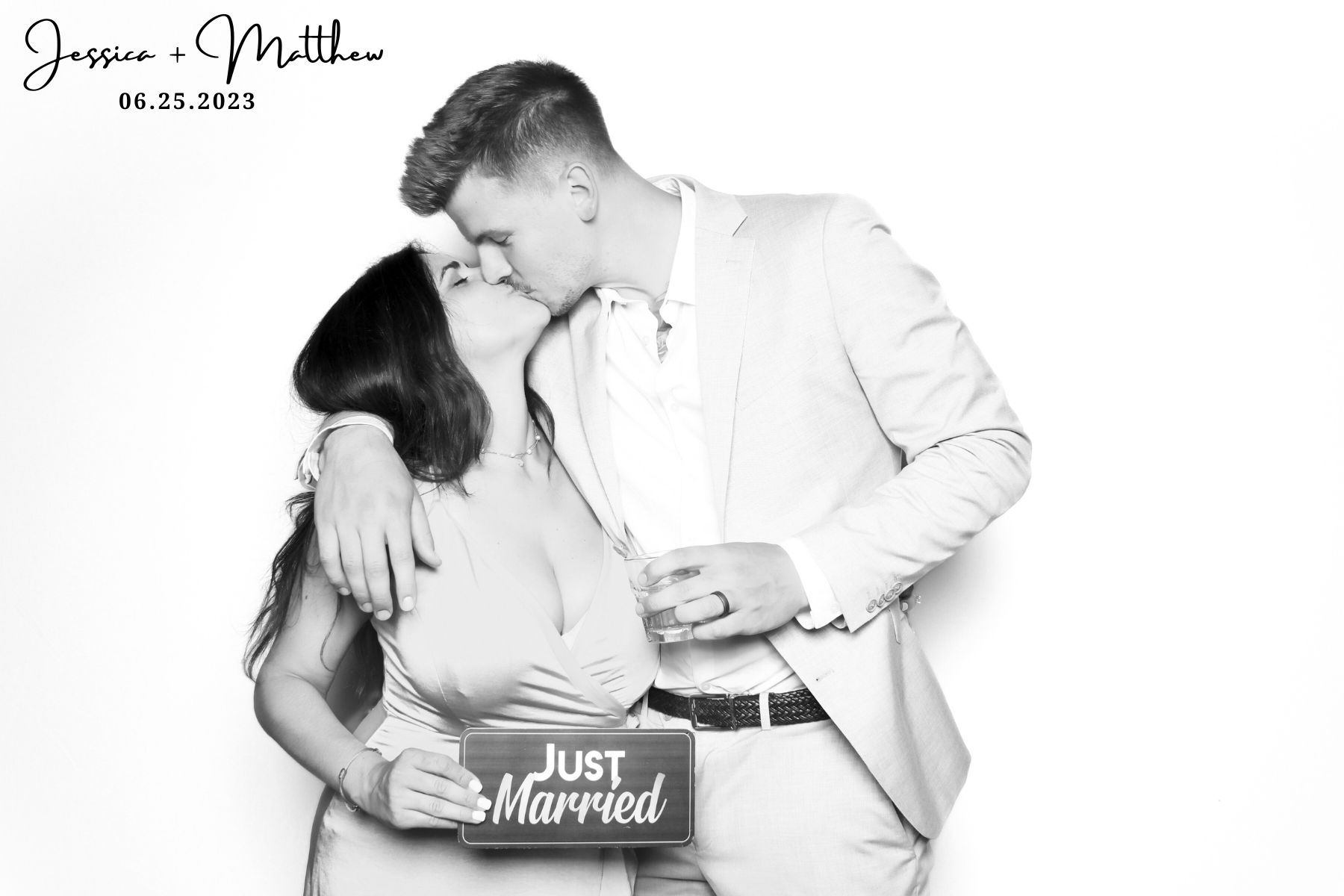 A black and white maternity photo of a couple embracing while holding a 'Just Married' sign.