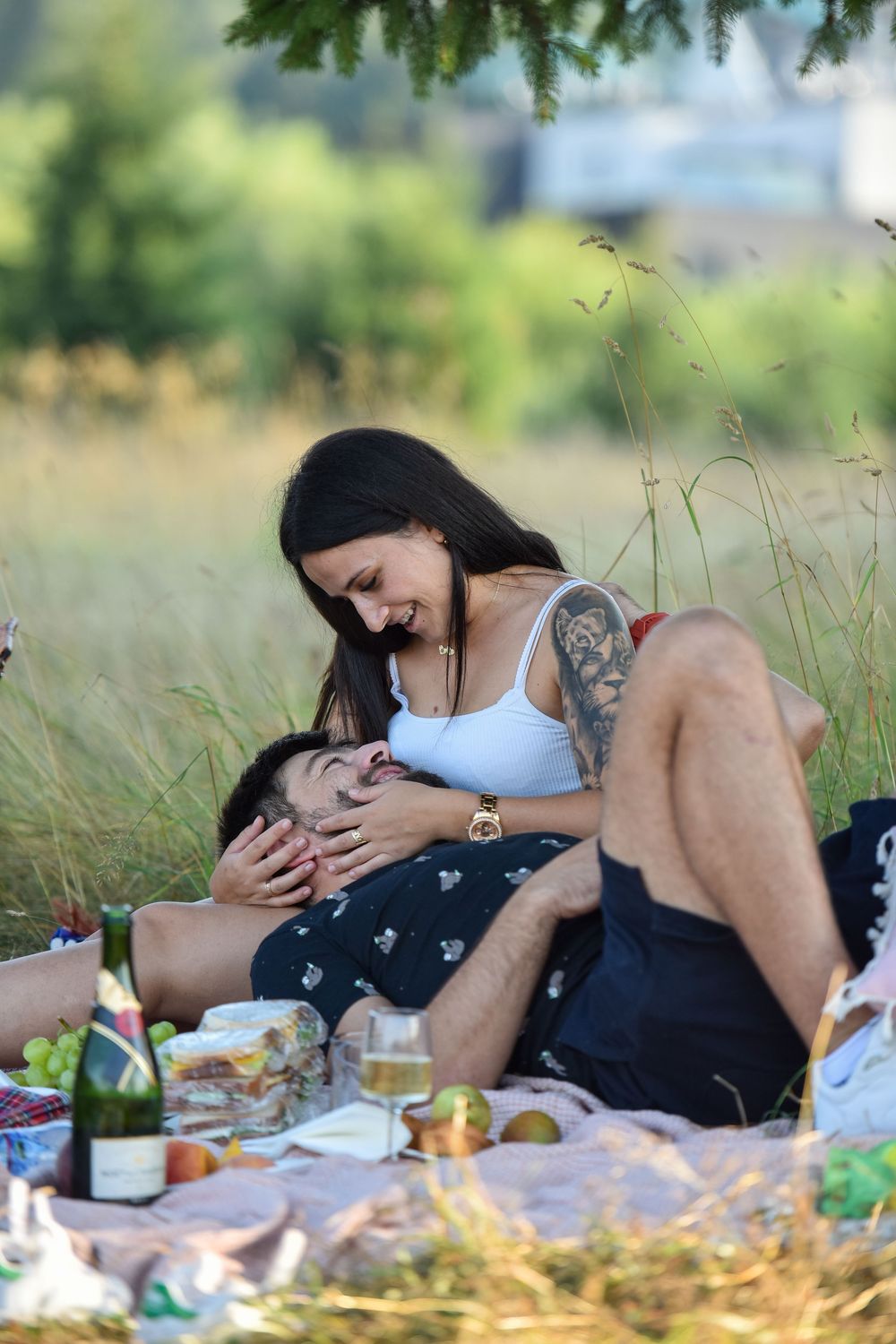 A romantic couple shares an intimate moment during a summer picnic in a grassy meadow.