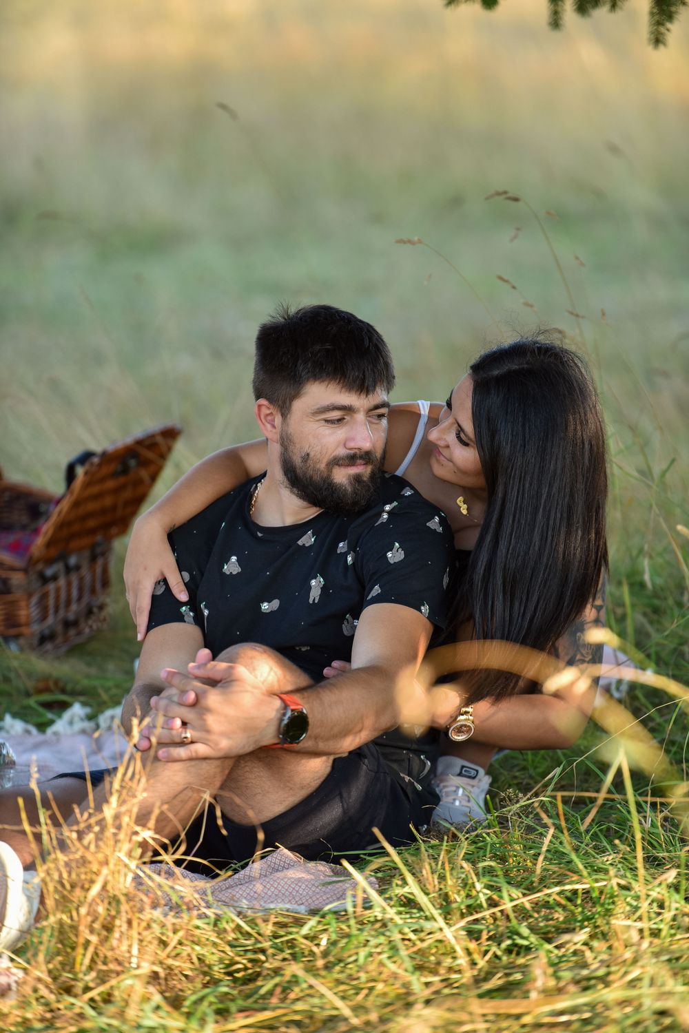 A couple shares an intimate moment while lying in golden grass during sunset.
