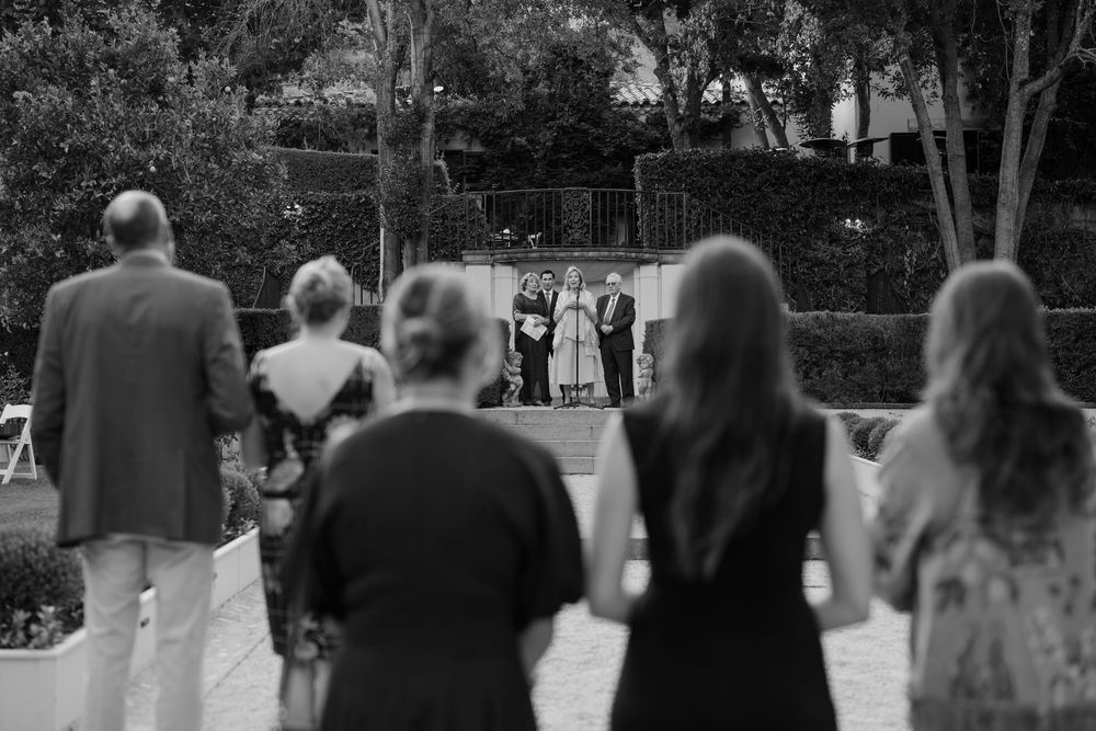 A black and white photo shows a crowd of people walking in a park or outdoor gathering space.