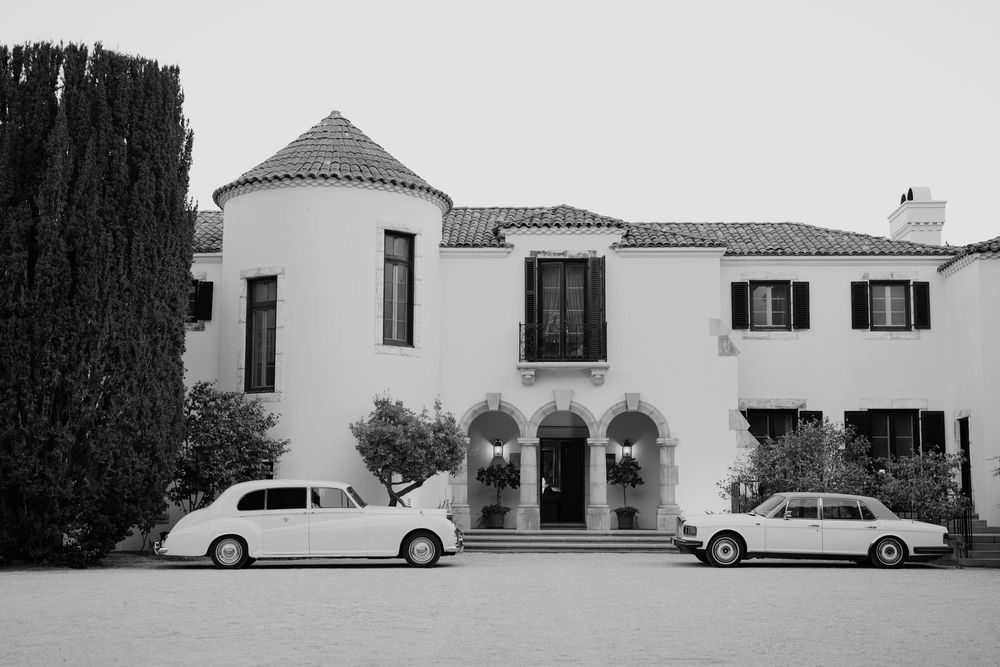 A panoramic view of white Spanish-style buildings with classic cars parked outside.