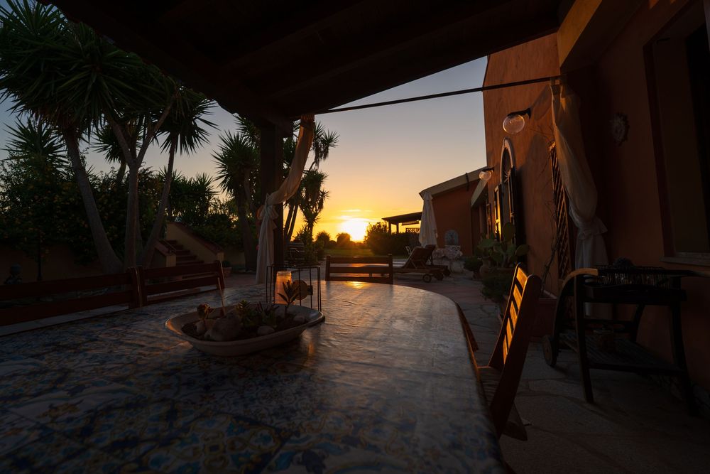 Stone patio with fire pit and outdoor furniture at sunset with warm ambient lighting.