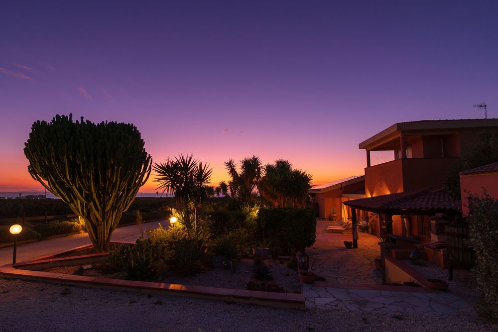 Panoramic sunset view of suburban houses silhouetted against purple and orange sky.