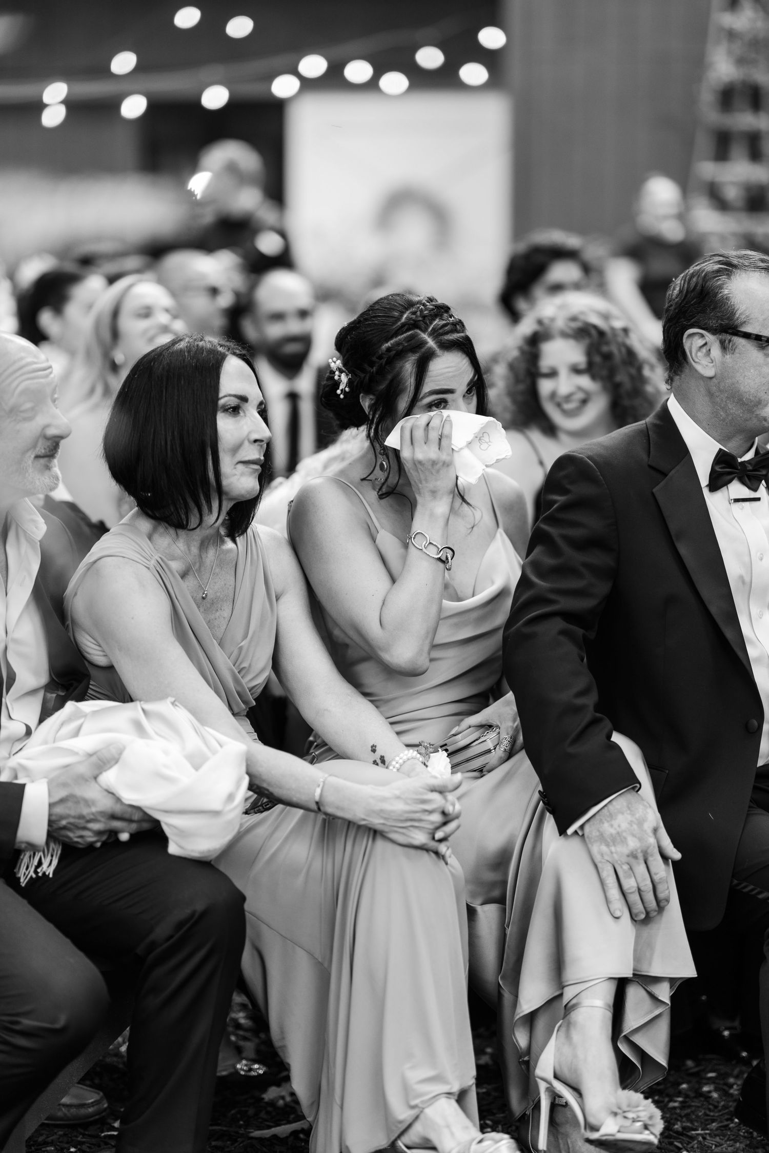 A sequence of black and white wedding photos showing joyful candid moments between guests during a celebration.