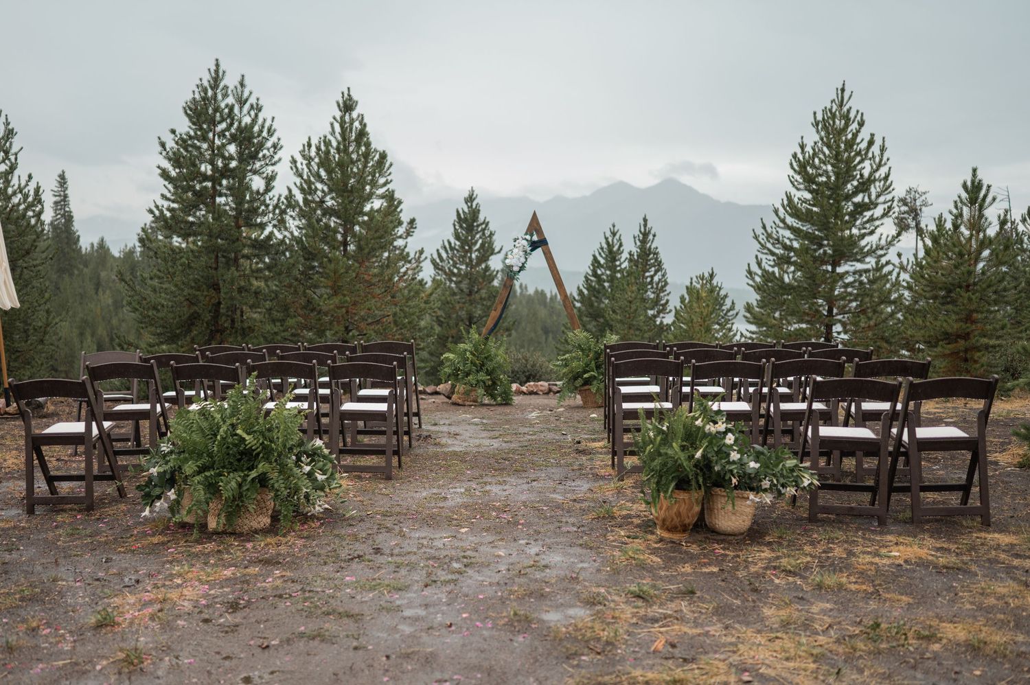 Snow-covered outdoor patio with wooden furniture and evergreen trees in the background on a cloudy winter day.