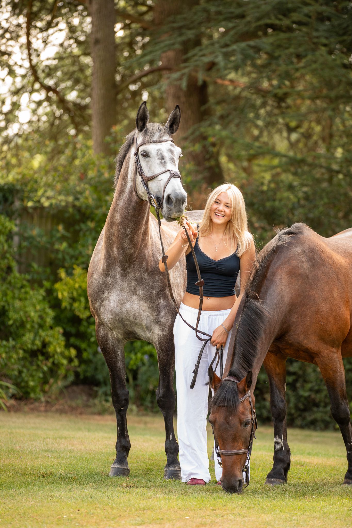 Young girl in denim overalls embraces a palomino horse in a sun-dappled forest setting.
