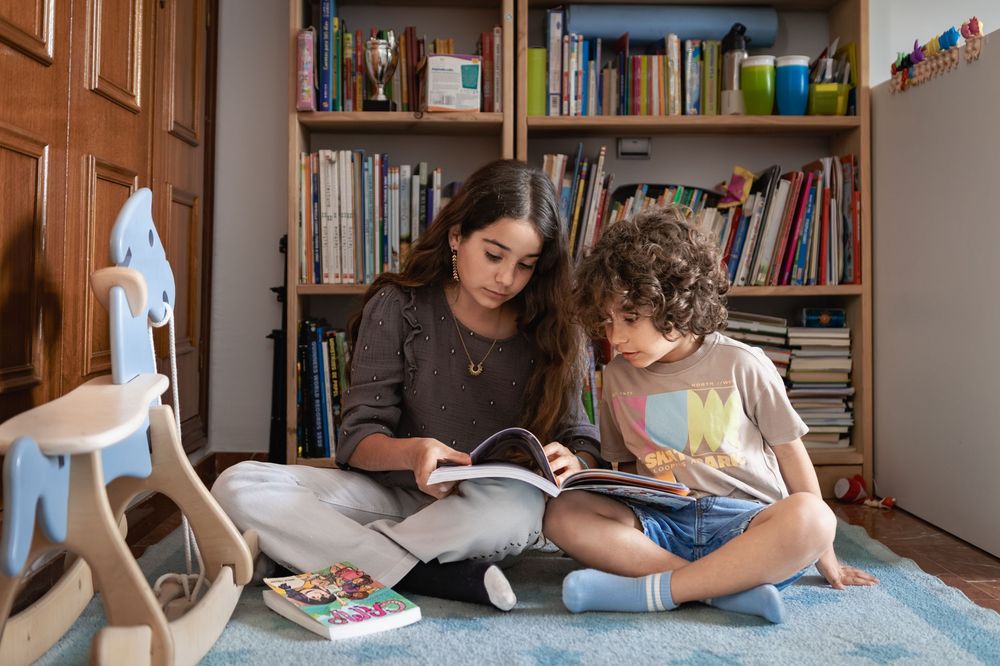 People studying together in a cozy home library with bookshelves and natural lighting.