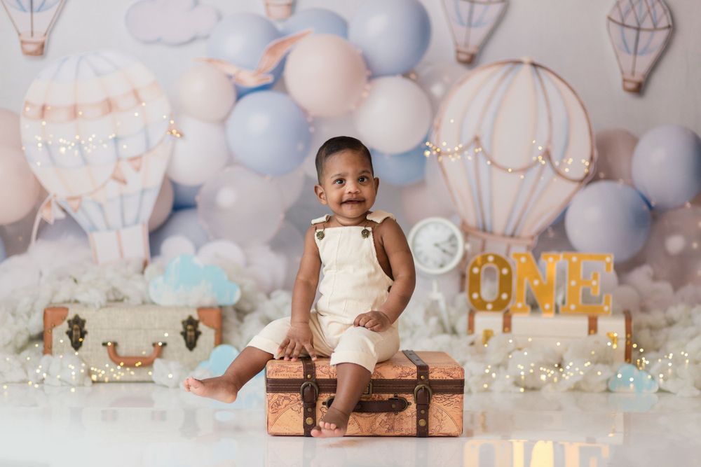 Hot air balloon themed birthday setup with pastel blue decor and vintage suitcase prop.