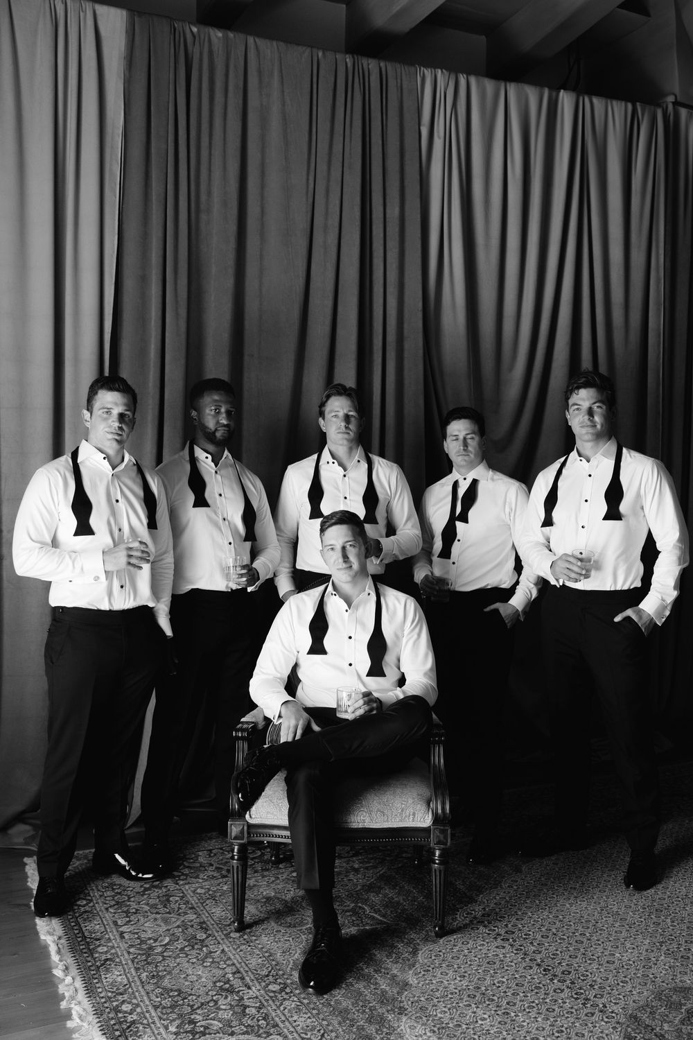 Multiple people in formal white shirts and dark pants sit in chairs arranged in a panoramic sequence.