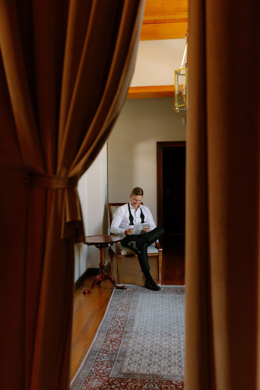 A sequence of four photos showing a person checking their phone while walking down a hallway with brown curtains.