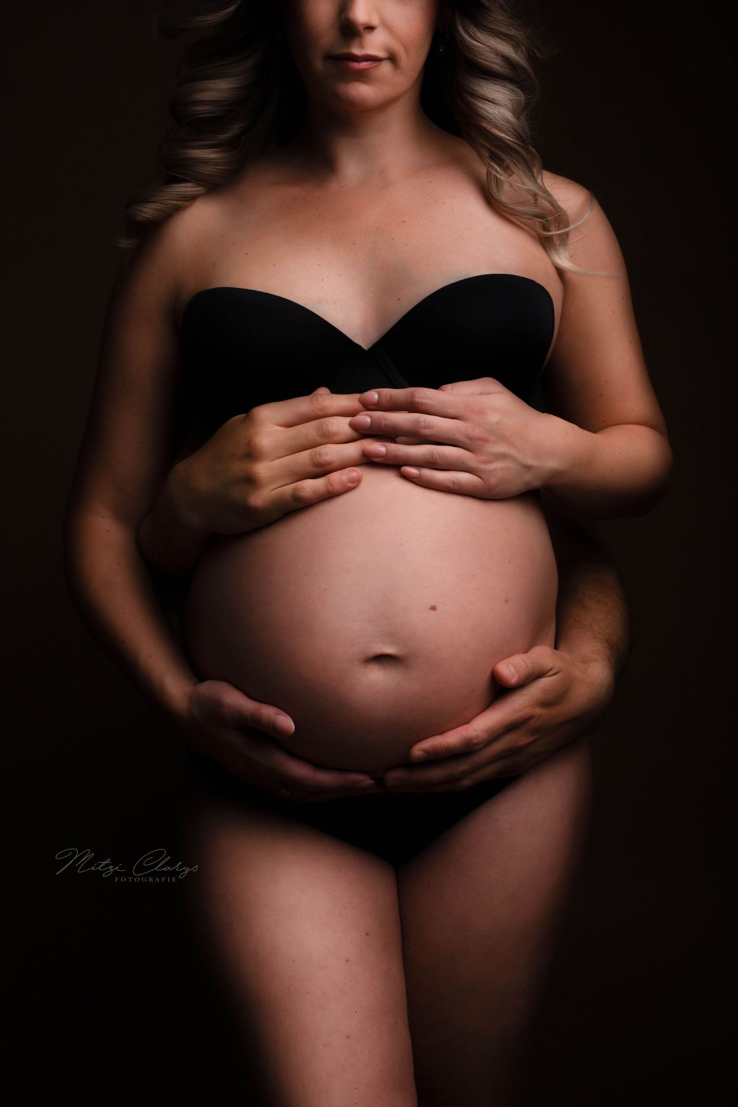 Zwangerschapsshoot met handen van ouders op de buik