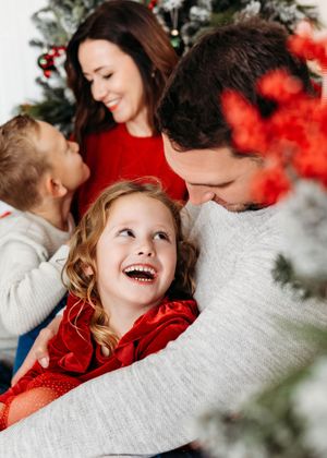 A festive family photoshoot with red and white holiday decor showing joyful candid moments and laughter.