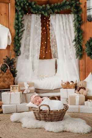 Cozy Christmas scene with white fur rugs, woven baskets and twinkling lights against rustic wooden walls and white curtains.