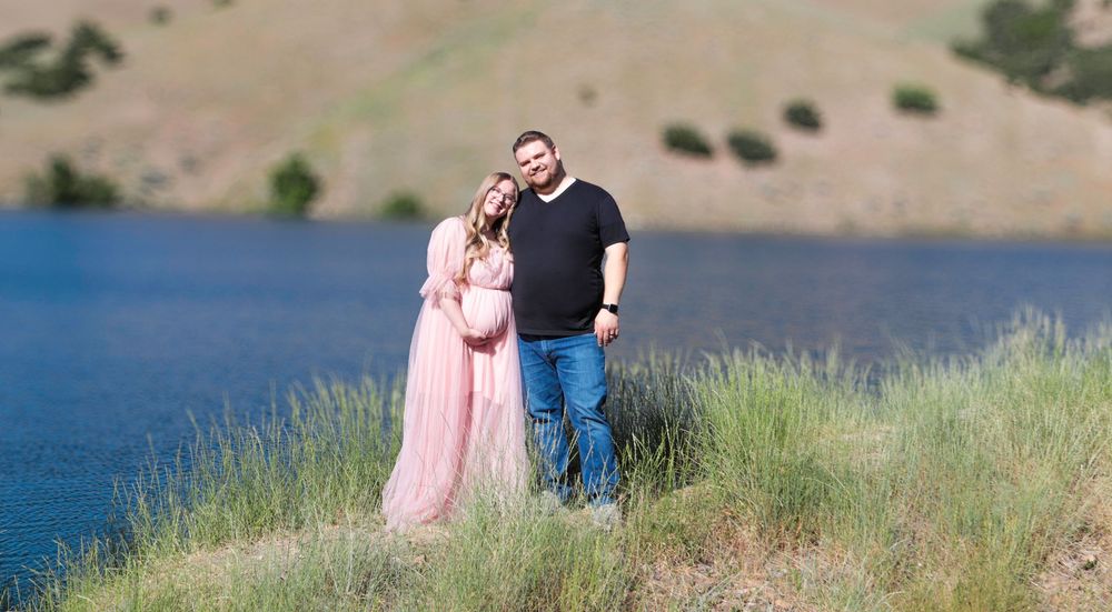 Expecting couple standing by a lake during a maternity photography session in Utah