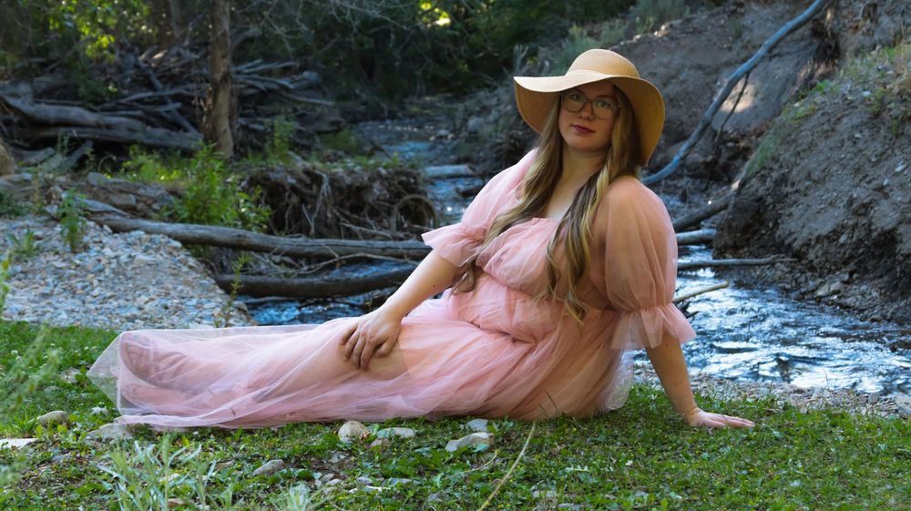Expecting mother posing by a creek during an outdoor maternity session in Utah