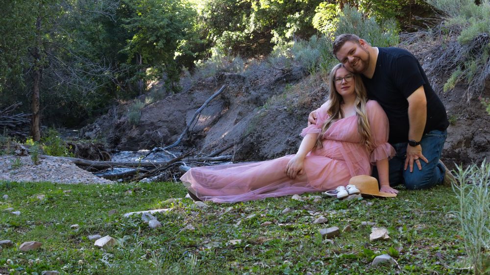 Couple sitting together during a candid outdoor maternity photo session