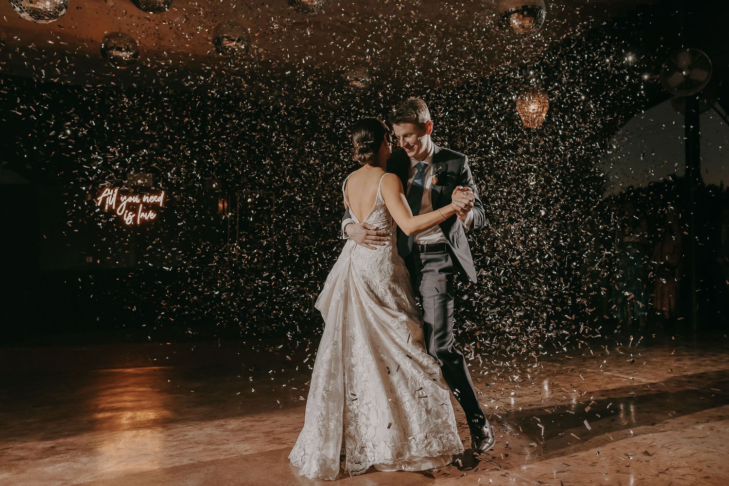 Wedding couple dancing amid falling confetti in a romantic evening celebration.