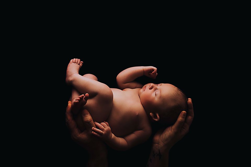 Black and white artistic photo series showing close-up details of a baby's feet and hands against a dark background.