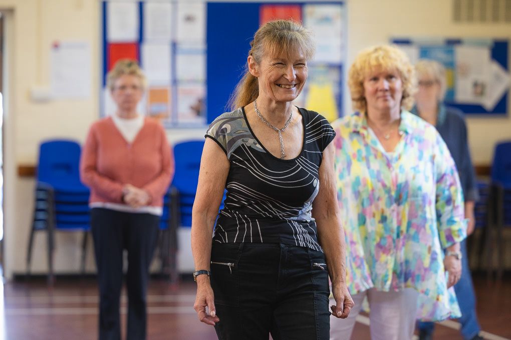 People participating in a group dance class in a bright studio with mirrors and wooden floors in Letchworth Garden City