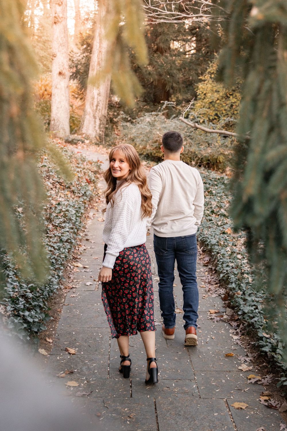 A couple walking together on a stone path through a romantic garden setting in autumn.