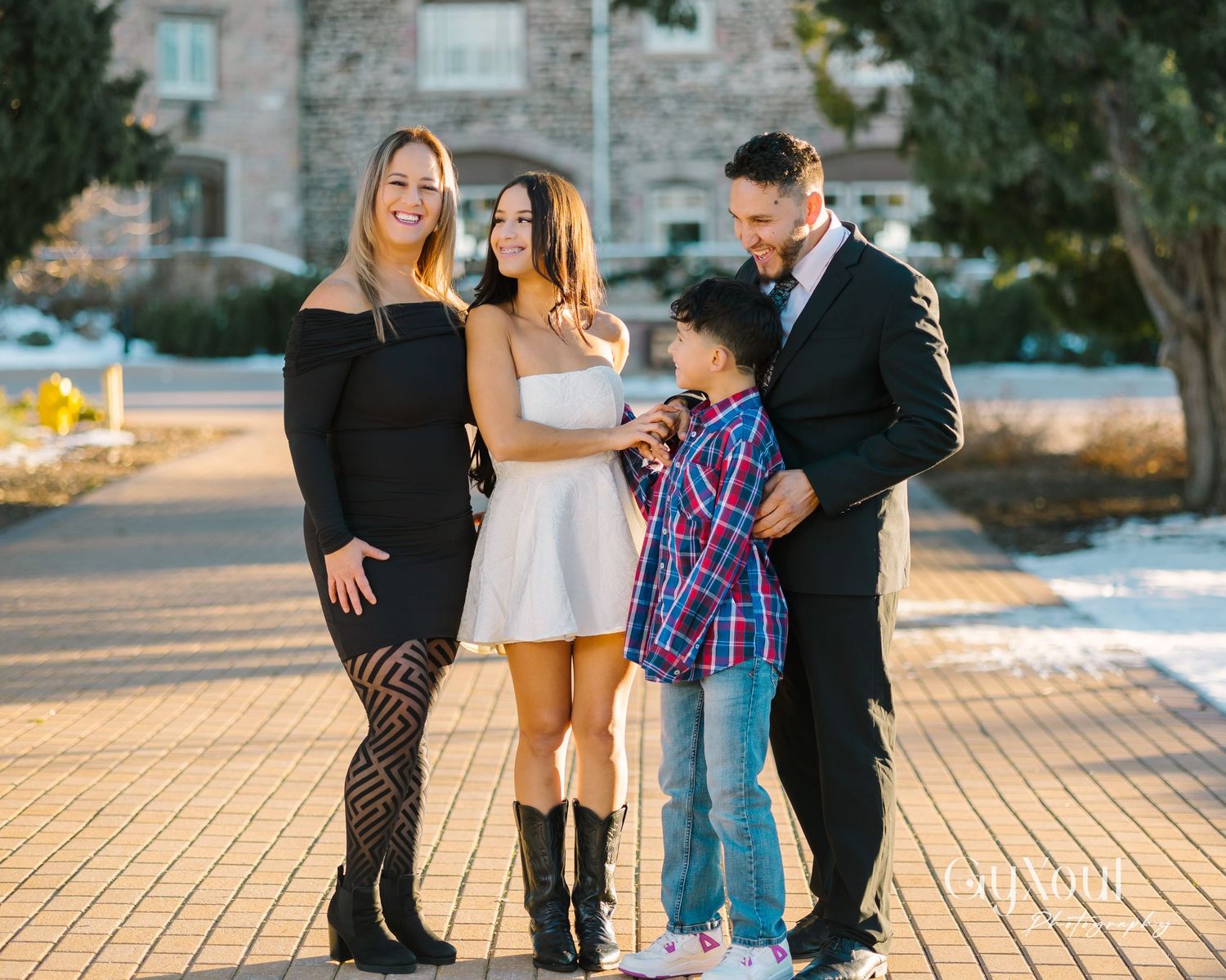 Family of four posing together outdoors in coordinated outfits.