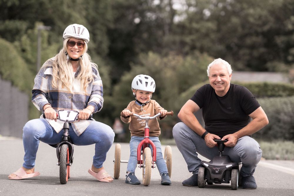 Familie fährt gemeinsam mit Kinderschutzhelmen Fahrrad auf dem Weg.