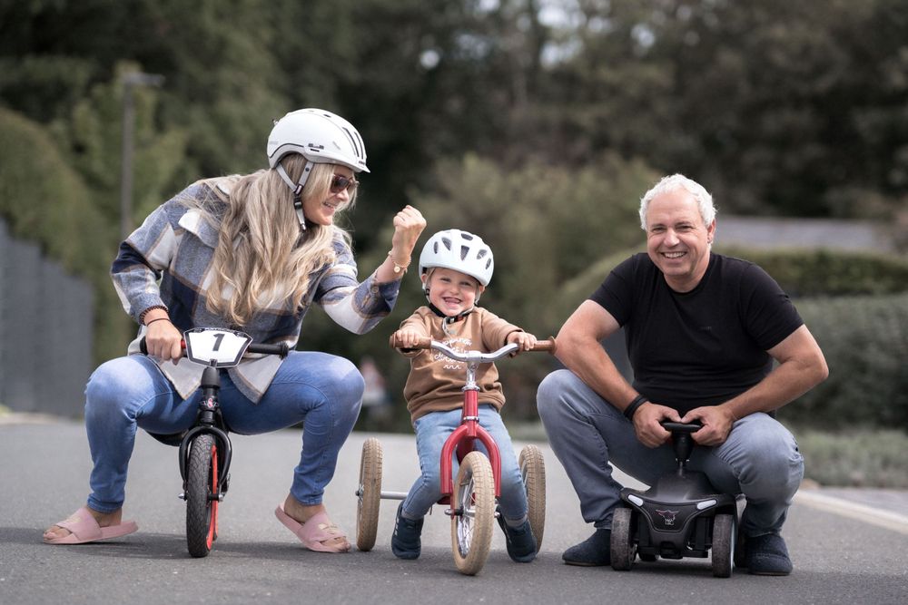 Lustige Fahrradszene für die ganze Familie mit Stützrädern und Schutzausrüstung.
