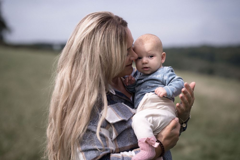 Ein zärtlicher Moment zwischen Erwachsenem und Baby im Freien auf einer Wiese.