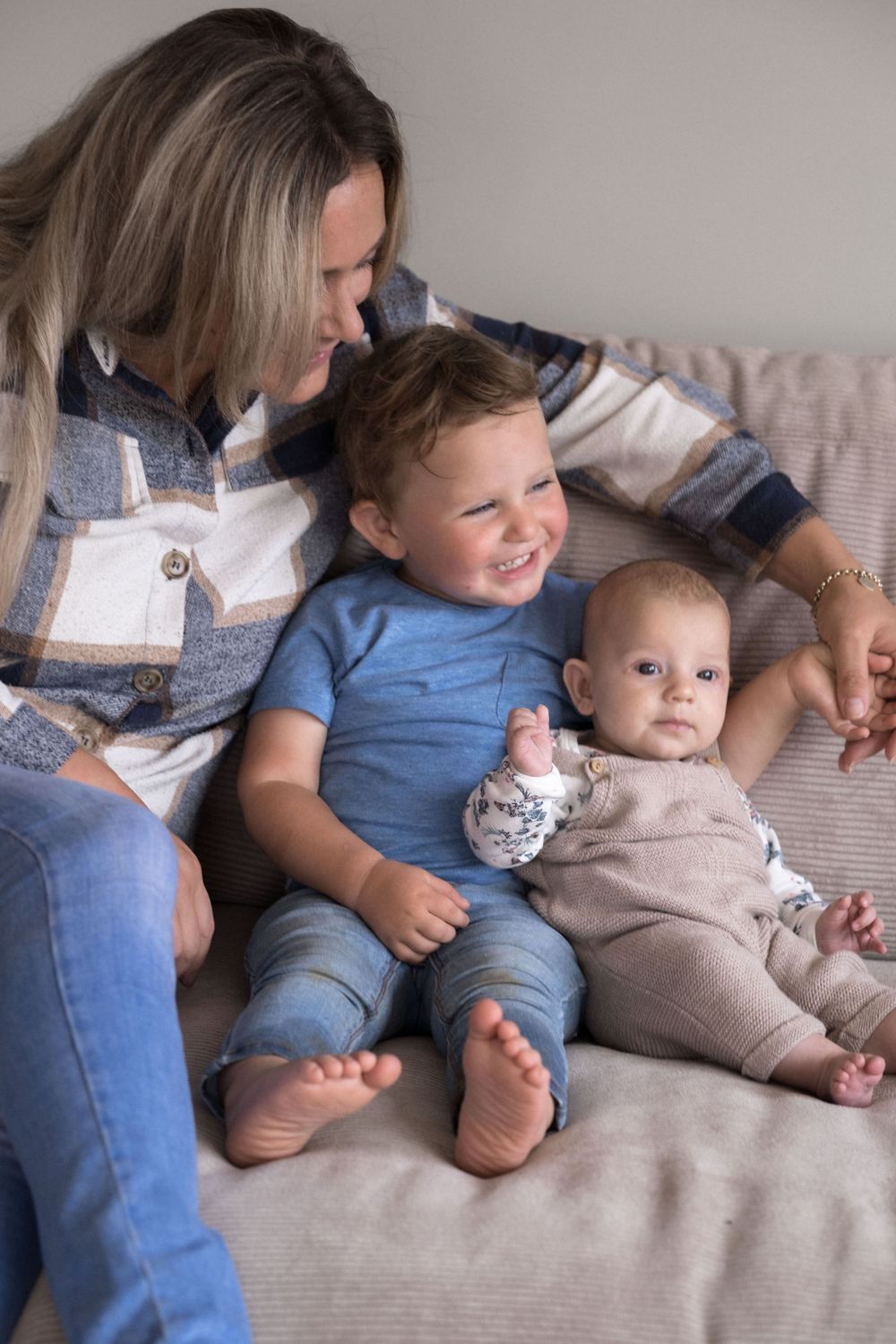 Ein gemütlicher Familienmoment mit Kindern, die gemeinsam auf einem grauen Sofa entspannen.