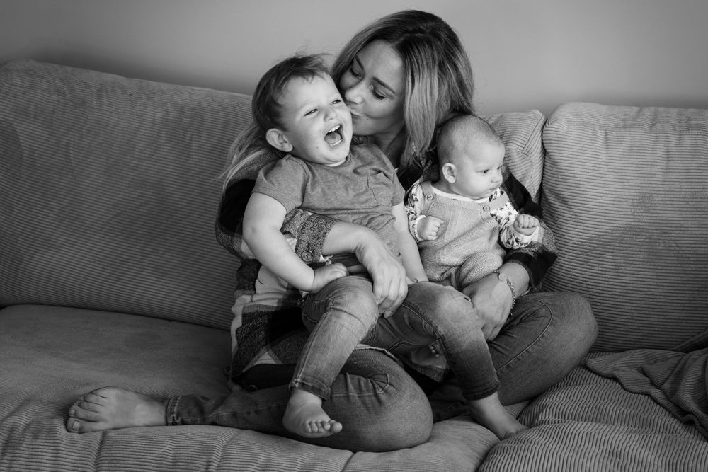 Ein spontanes Schwarzweißfoto von fröhlichen Familienmomenten auf einem Sofa.