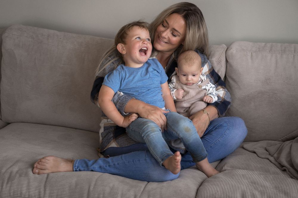 Ein herzerwärmender Familienmoment voller Lachen und Nähe auf einem weichen, grauen Sofa.