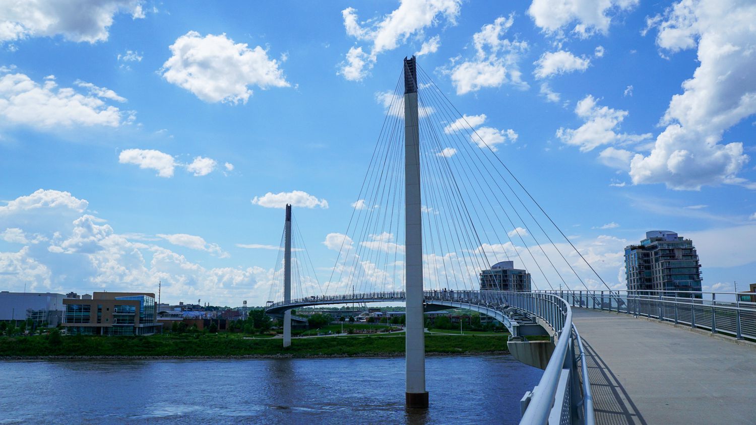 Bob Kerry Pedestrian bridge spanning across the Missouri River on a sunny day with blue skies and white clouds.