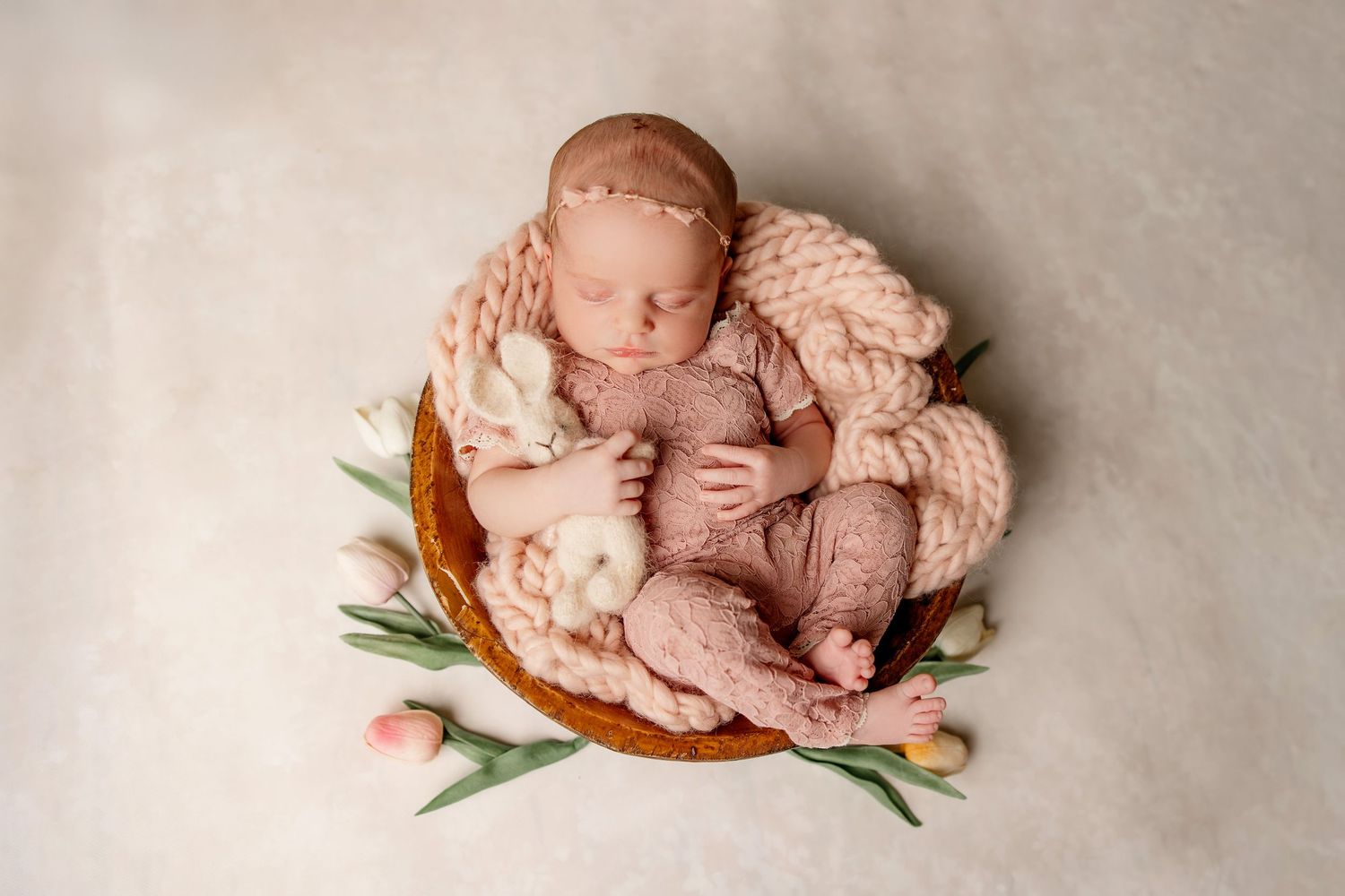 A newborn photography setup with Harry Potter themed props and knitted accessories in a basket.