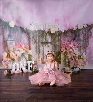 Floral first birthday setup with pink tulle dress and rustic white furniture.