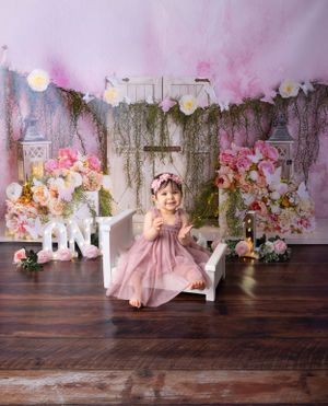 Birthday photo scene with pink flowers, white furniture and ONE letters on wooden floor.