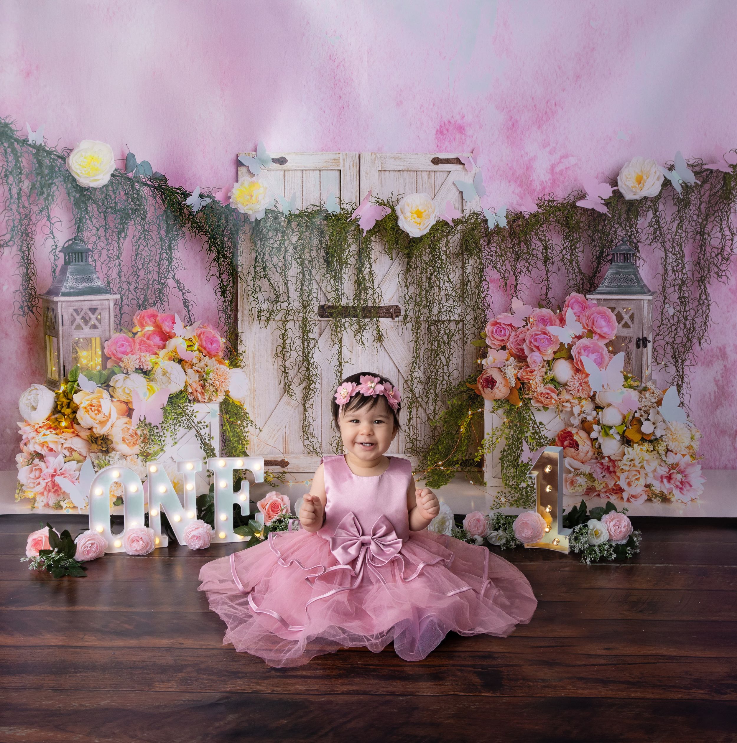 Pink floral backdrop with rustic wood elements sets a dreamy scene for photography.